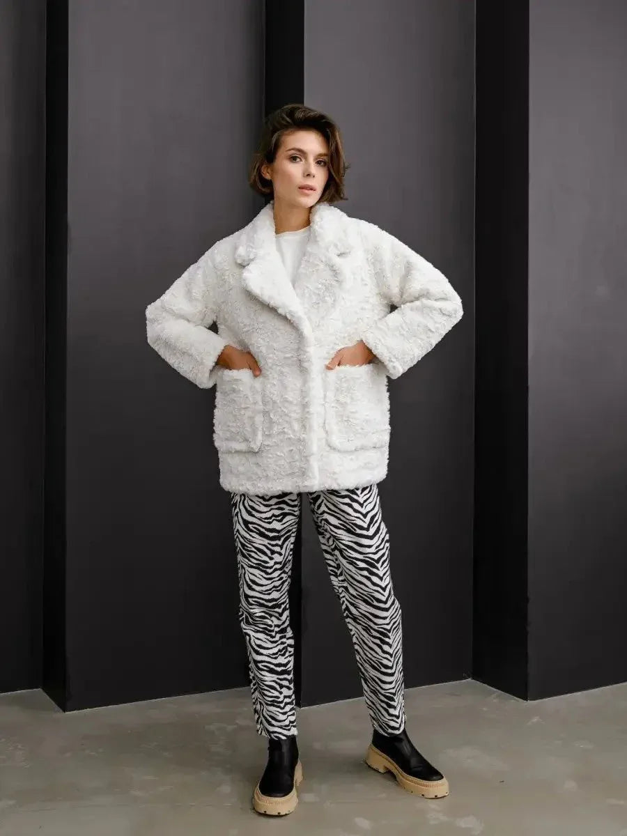 Woman in a white textured faux fur jacket with hands in pockets
