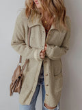 Close-up of a woman adjusting her beige textured knit cardigan.
