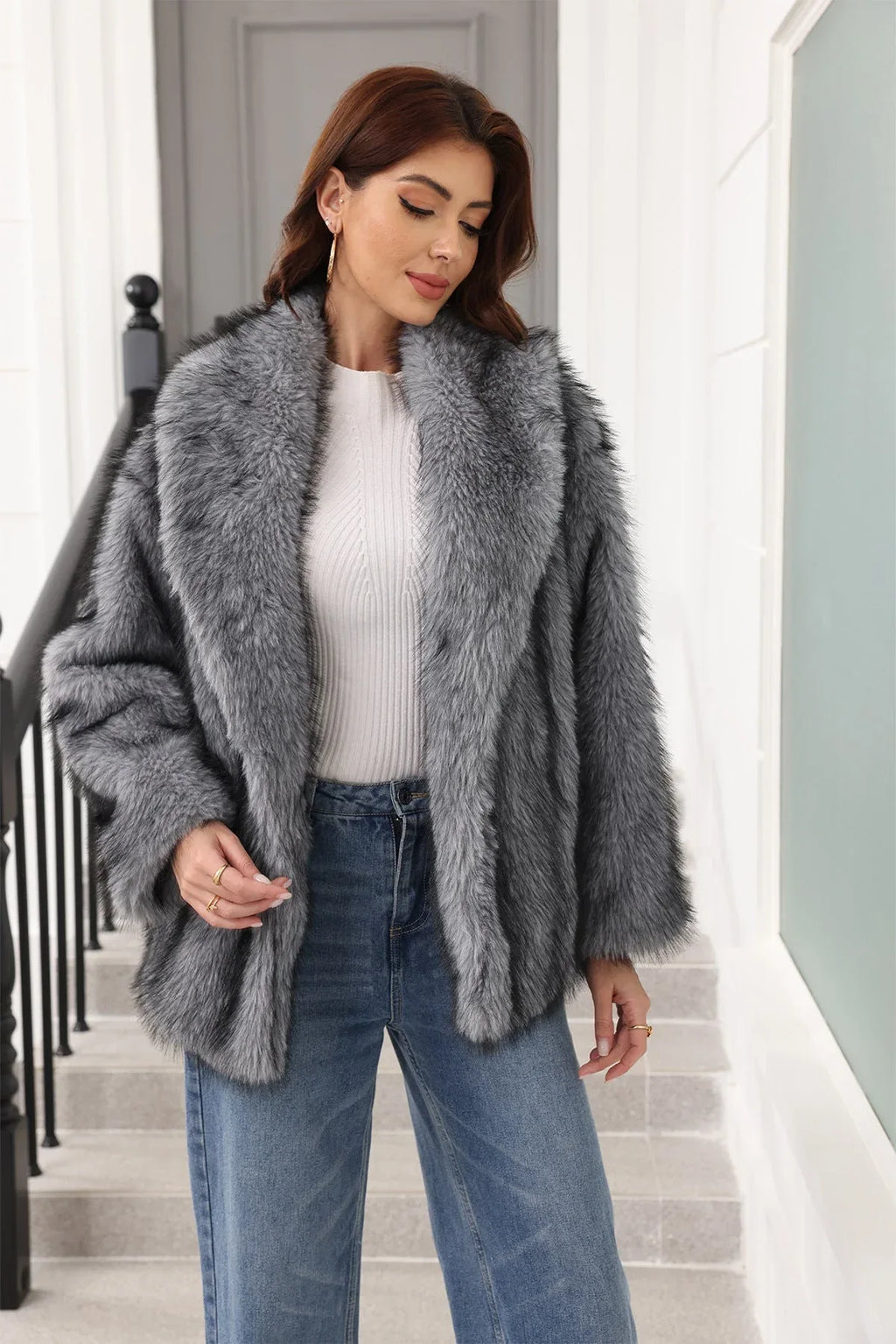 Woman in a grey faux fur jacket with a belted waist and notched lapel, smiling.