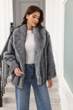 Woman in a grey faux fur jacket with a belted waist and notched lapel, smiling.