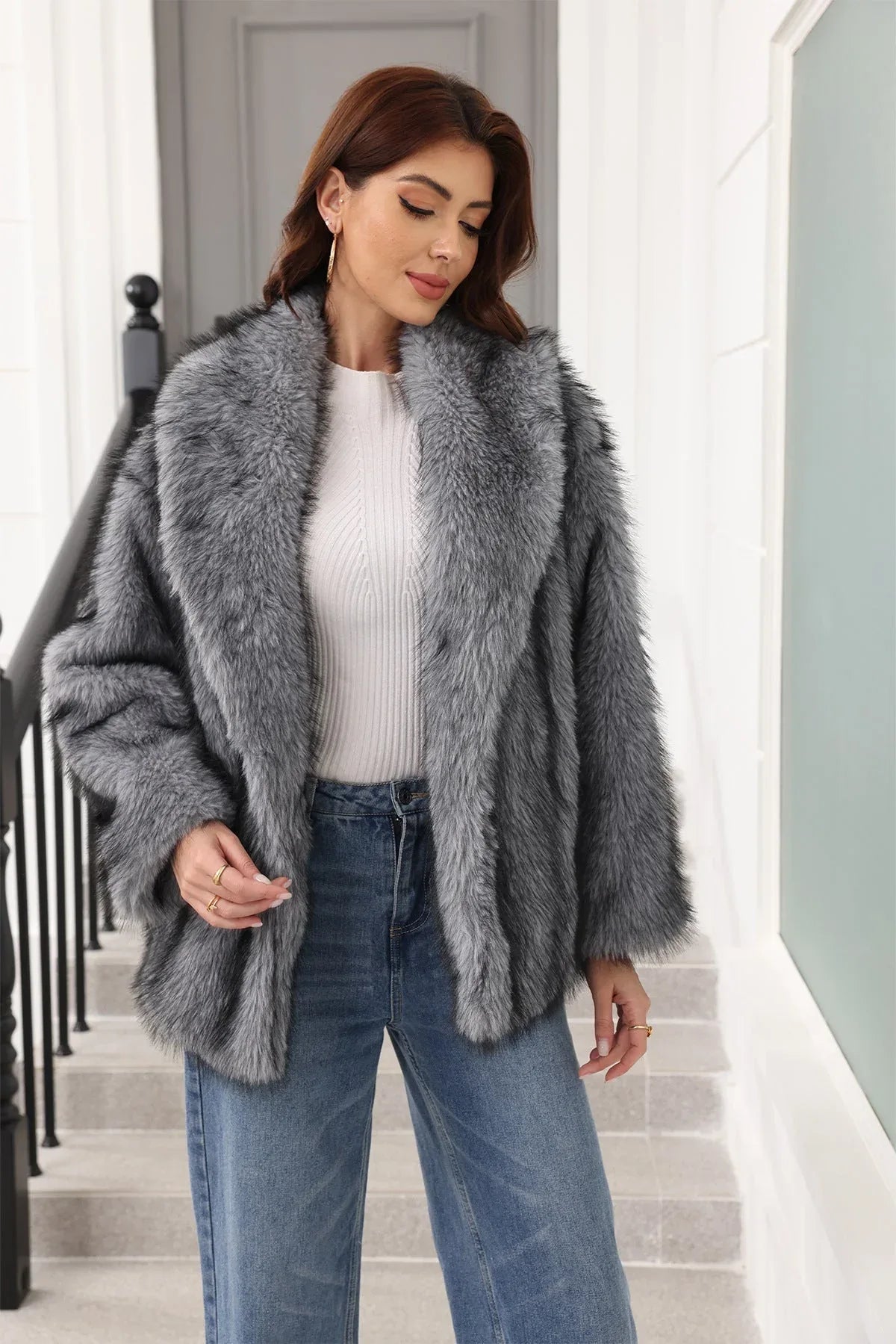 Woman in a grey faux fur jacket with a belted waist and notched lapel, smiling.