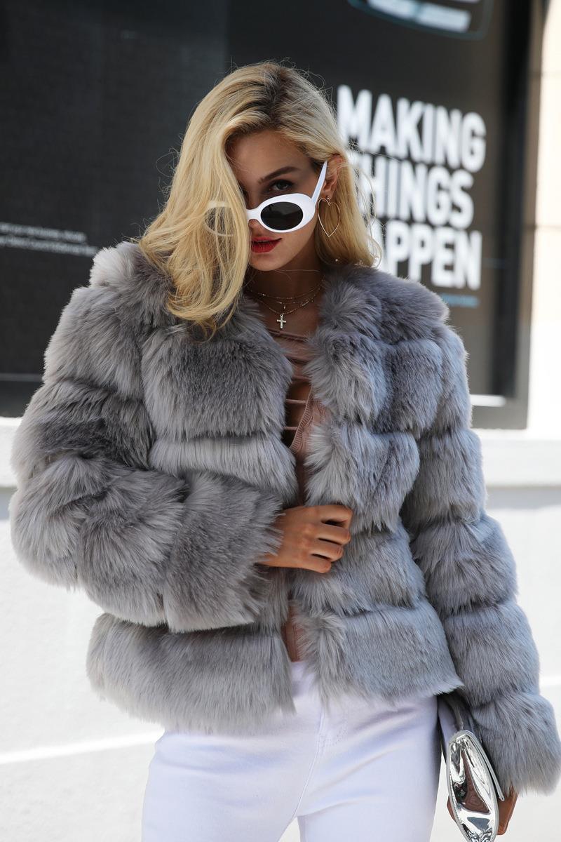 Woman wearing a grey faux fur cropped jacket with white pants and sunglasses