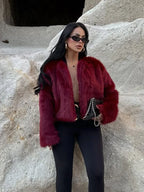 Woman wearing a burgundy faux fur cropped jacket with an open front and long sleeves.