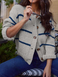 Woman wearing a light gray knit cardigan with navy blue stripes and wooden buttons.