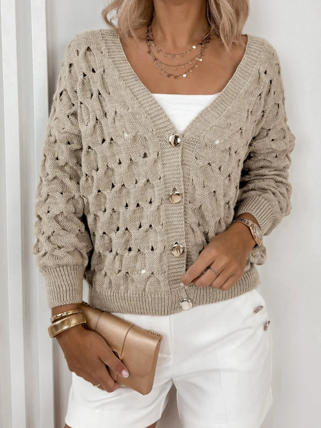Woman wearing a beige open-knit V-neck button-down cardigan with long sleeves.
