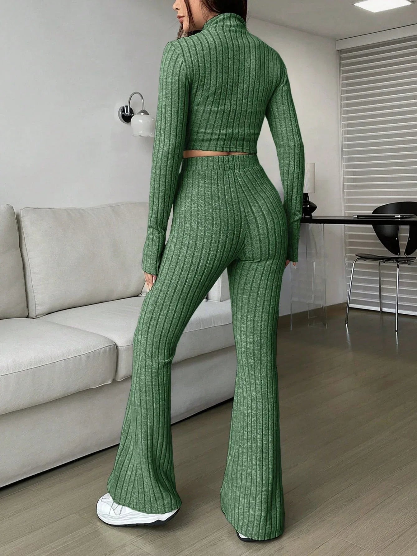 Back view of a woman in a green ribbed knit set with a cropped top and flared pants
