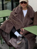 Woman in a brown faux fur coat with a white t-shirt and black leggings.