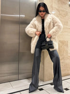 Woman posing in a cream faux fur coat.