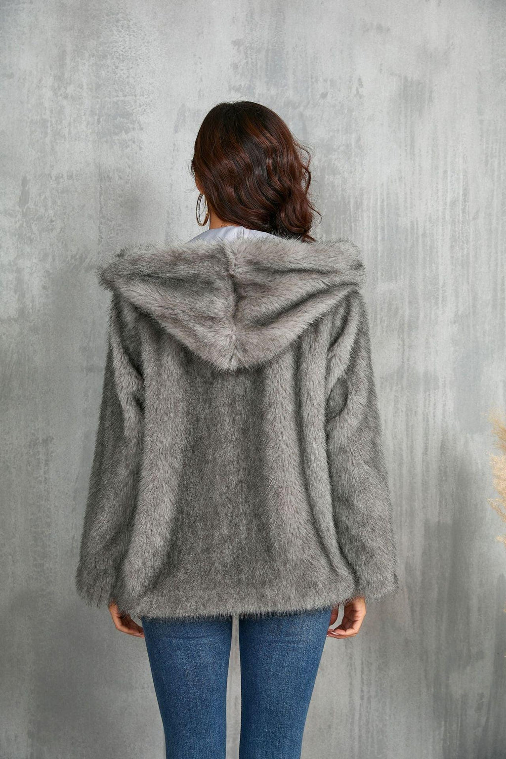 Woman wearing a grey faux fur hooded jacket, back view