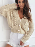 Close-up of a beige cropped knit cardigan with intricate open knit and cable knit details.