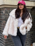 Full body shot of a woman in a cream faux fur jacket and dark jeans, standing outdoors.