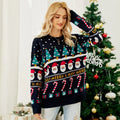 Woman in a festive Christmas sweater posing in front of a decorated Christmas tree.