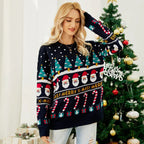Woman in a festive Christmas sweater posing in front of a decorated Christmas tree.