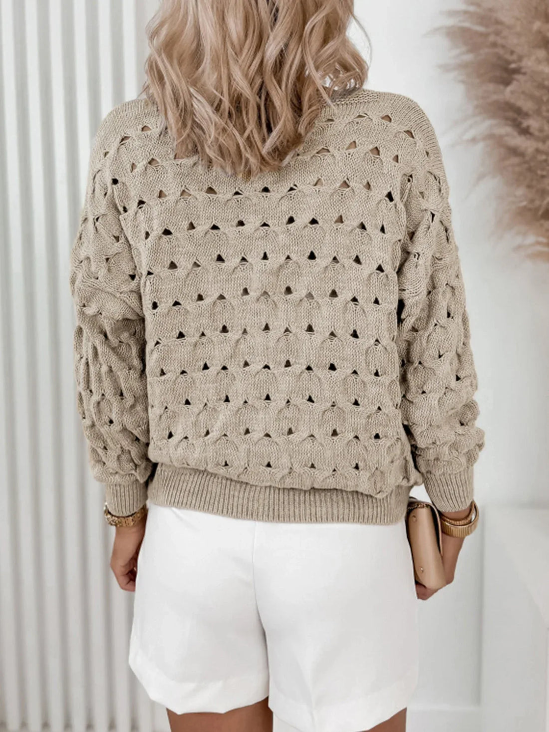 Woman wearing a beige open-knit V-neck button-down cardigan with long sleeves.