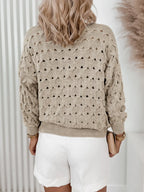 Back view of a woman in a beige open-knit cardigan with a repeating diamond pattern.