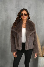 Woman posing in a brown faux fur cropped jacket, sunglasses and gold jewelry