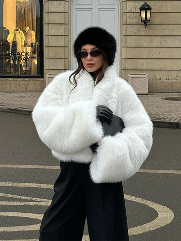 Woman wearing a white fluffy faux fur cropped jacket with black pants and a black hat.