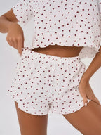 Woman adjusting the waistband of her pajama shorts, which have a heart print and elastic band.