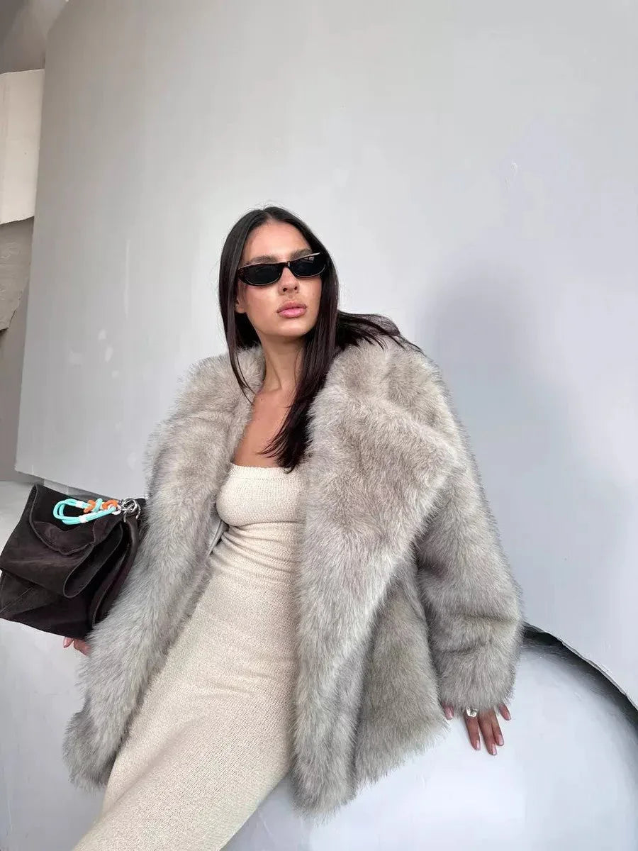 Woman wearing a luxurious grey faux fur coat with an oversized lapel and a cream-colored knit dress.