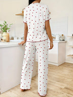 Back view of a woman wearing white pajama set with red hearts and red trim, standing in a kitchen.