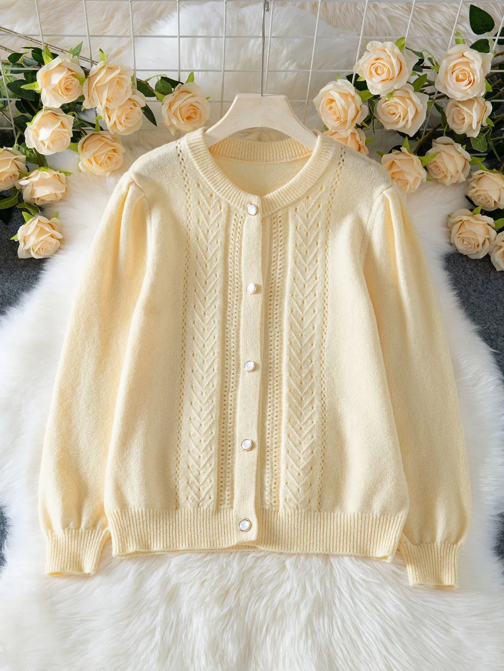 Light yellow knit cardigan with puff sleeves and button front laid flat