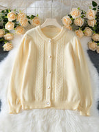 Light yellow knit cardigan with puff sleeves and button front laid flat