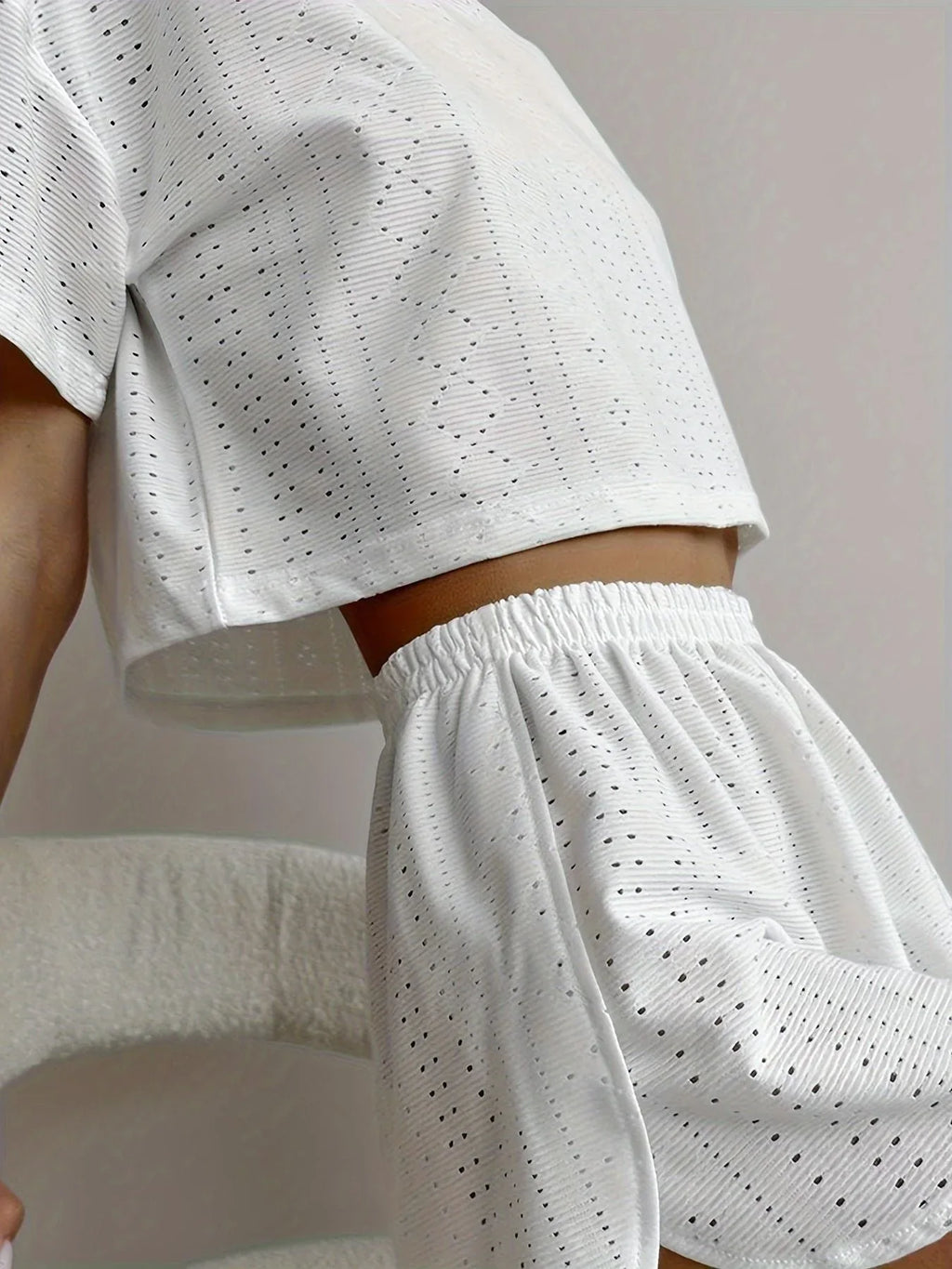 Close-up of a woman's torso showing the cropped eyelet t-shirt and elastic waistband shorts