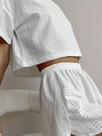 Close-up of a woman's torso showing the cropped eyelet t-shirt and elastic waistband shorts