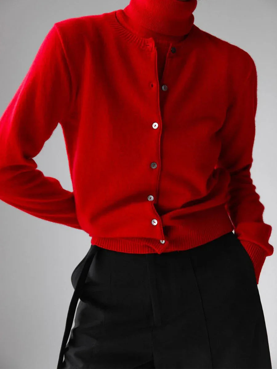 Woman wearing a red fine knit cardigan over a red turtleneck and black trousers