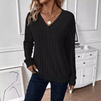 Front view of a woman in a black v-neck knit sweater.