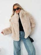 Woman wearing a beige faux fur cropped jacket with blue jeans