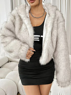 Woman in a white faux fur cropped hooded jacket, styled with a silver chain necklace