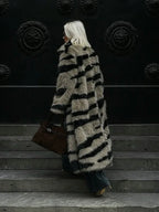 Back view of a woman walking down steps in a long faux fur coat with a striped pattern.