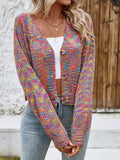 Woman wearing a rainbow multicolor open-knit cropped cardigan with a v-neck and button-front closure, paired with a white top and blue jeans.