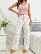 Full-body shot of a woman in a pink lace-trimmed tank top and floral print pajama pants