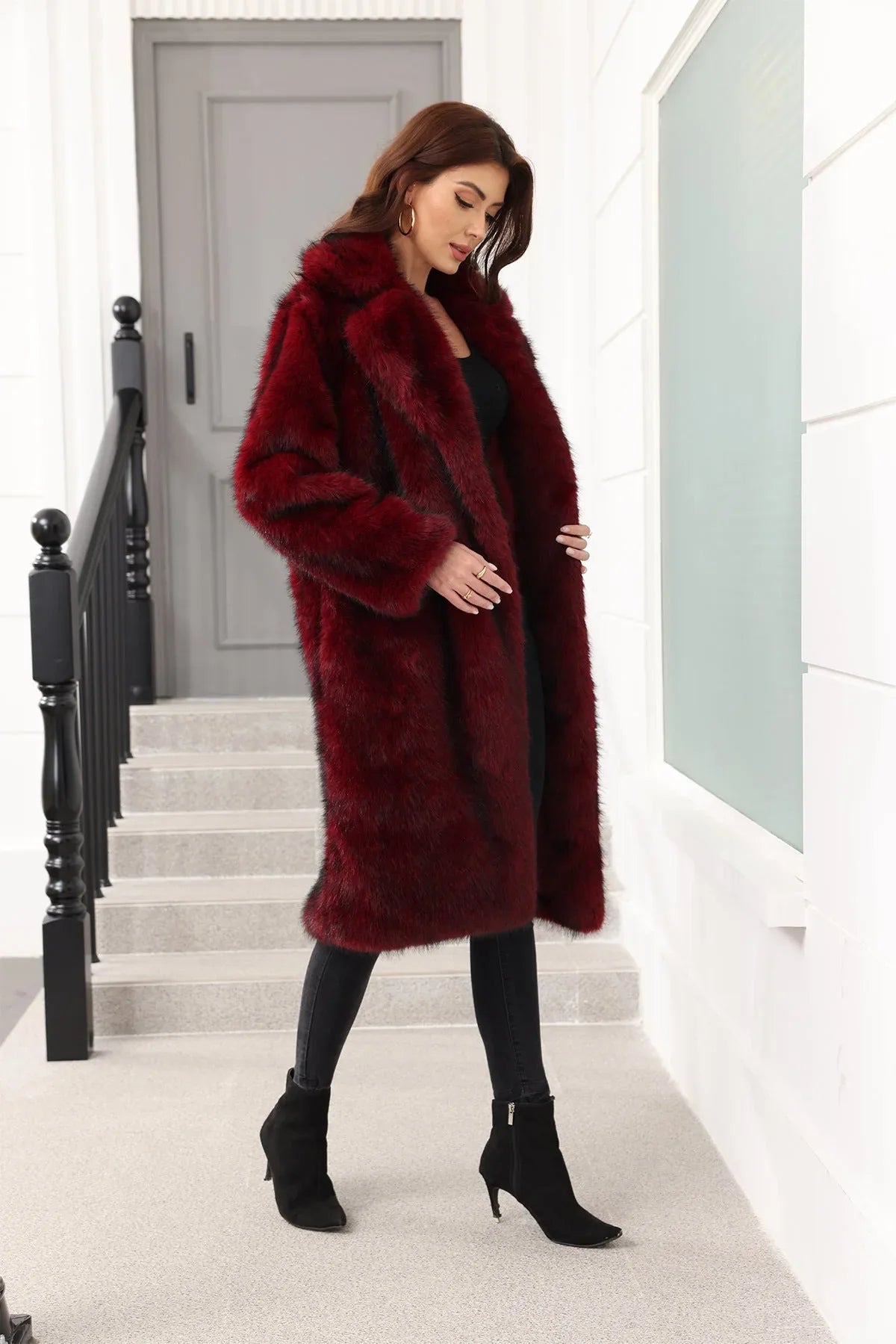 Woman in a dark red faux fur coat, showing the open front and side pockets, standing on stairs.