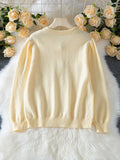 Back view of light yellow knit cardigan with puff sleeves laid flat