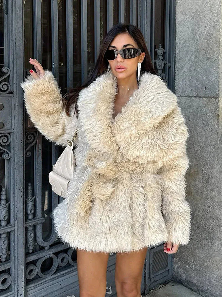 Woman wearing a cream-colored faux fur jacket with an oversized collar and a belted waist.