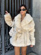 Woman wearing a cream-colored faux fur jacket with an oversized collar and a belted waist.