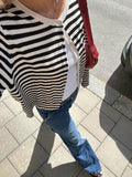 Overhead view of a woman in a striped cardigan and blue jeans on a sidewalk.