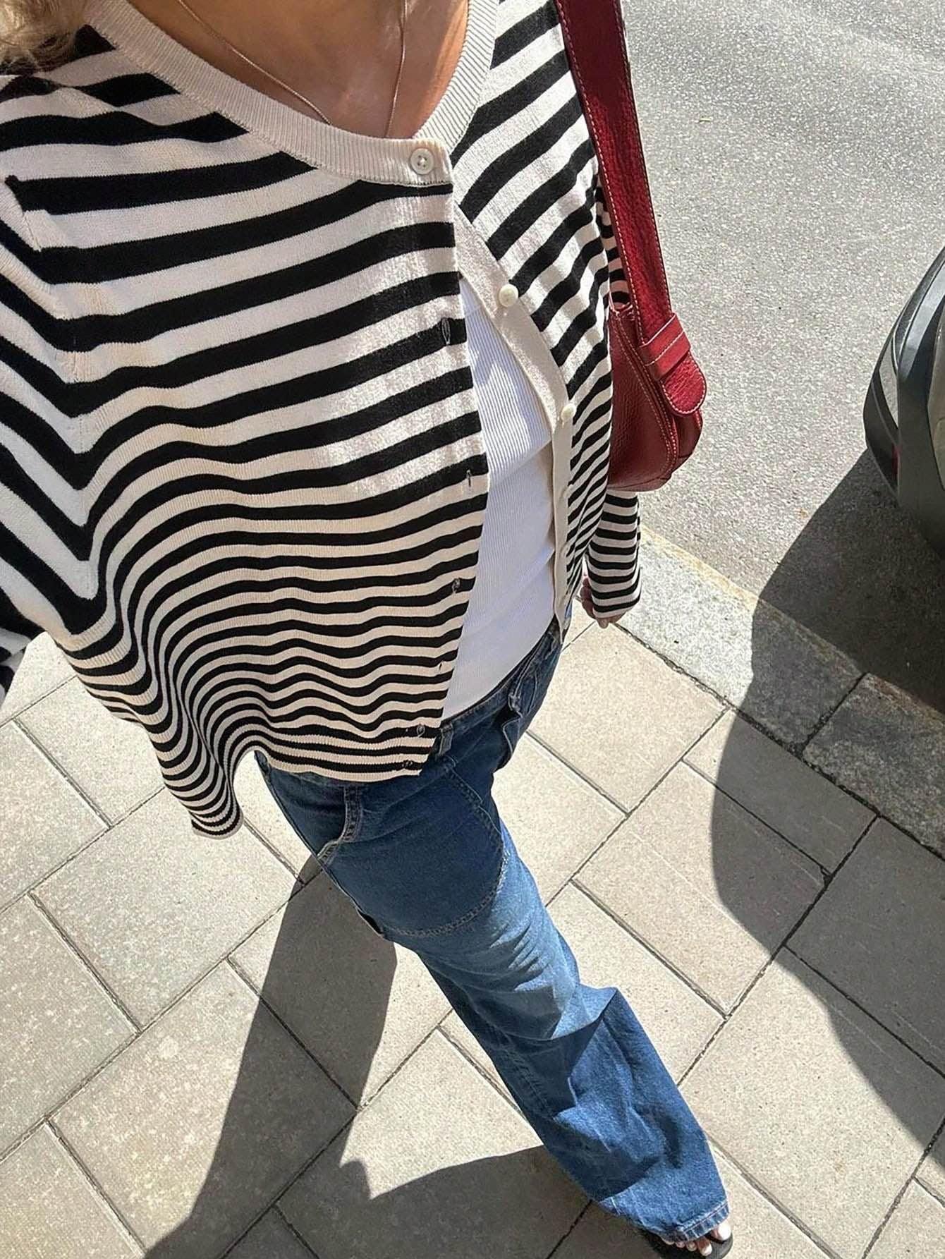 Overhead view of a woman in a striped cardigan and blue jeans on a sidewalk.