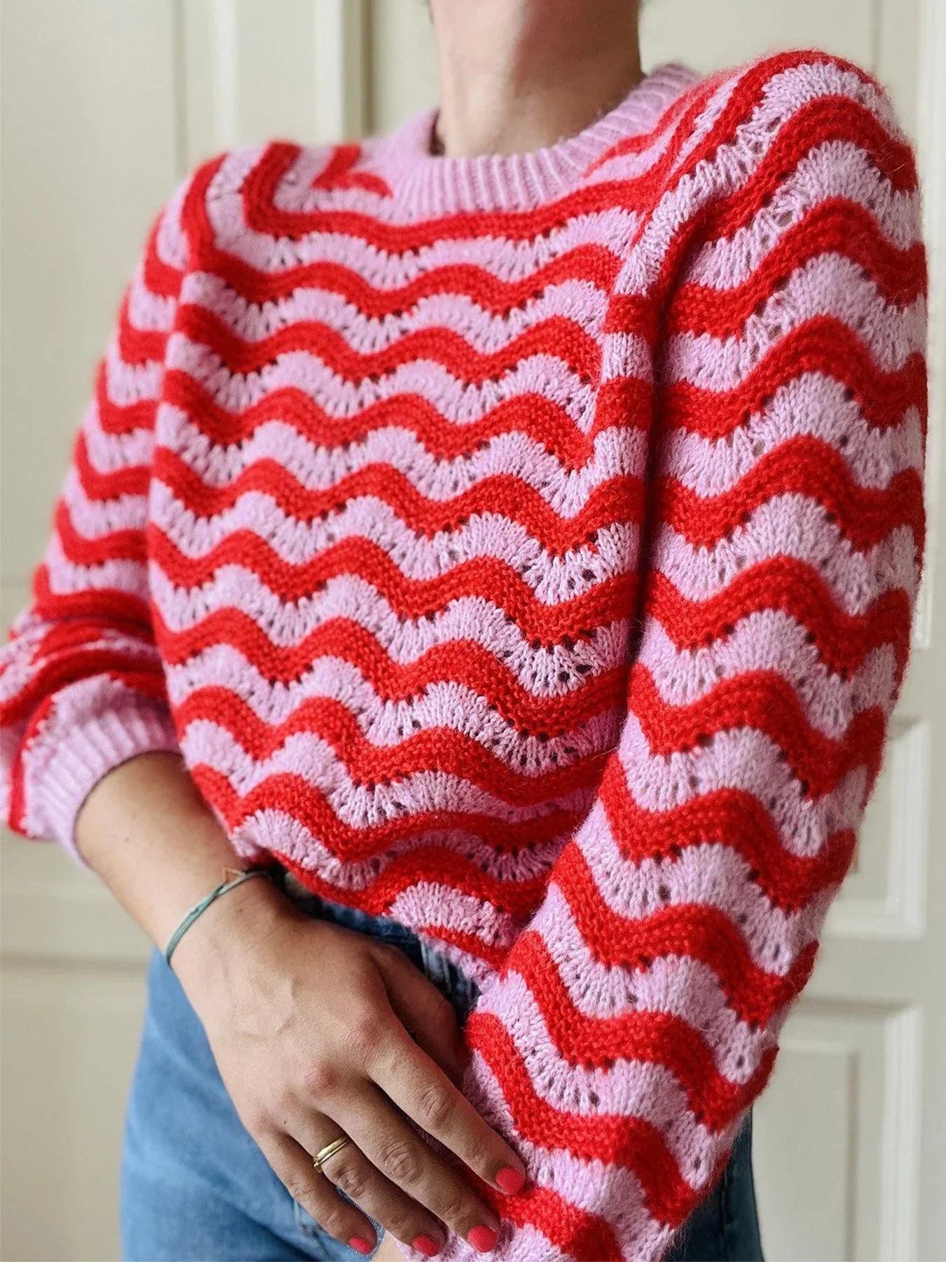 Front view of a woman in a red and pink patterned sweater and blue jeans