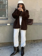 Woman wearing a brown faux fur hooded jacket and grey sweatpants.