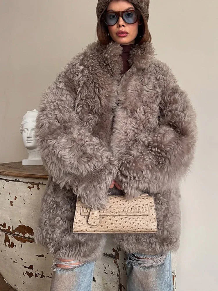 Front view of a woman in a grey curly faux fur coat, showcasing the textured fabric and relaxed fit.