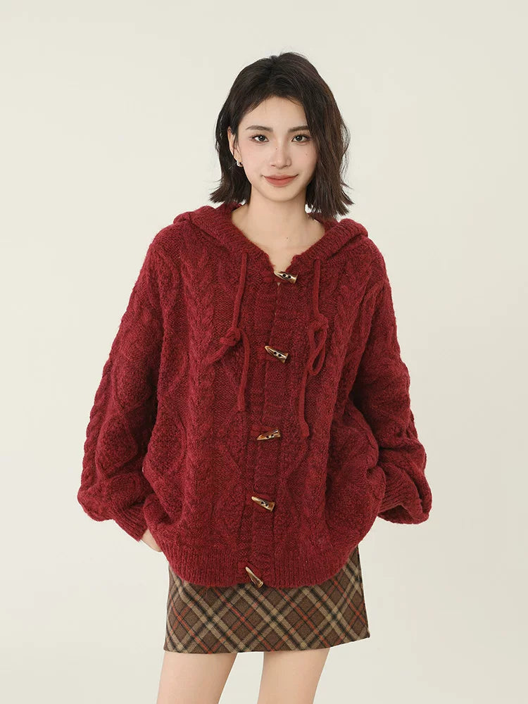 Woman wearing a red hooded cable knit cardigan with toggle buttons and a plaid skirt