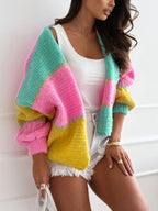 Woman wearing a multi-colored striped knit cardigan over a white tank top and denim shorts