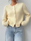 Woman posing in a light yellow knit cardigan and denim jeans.