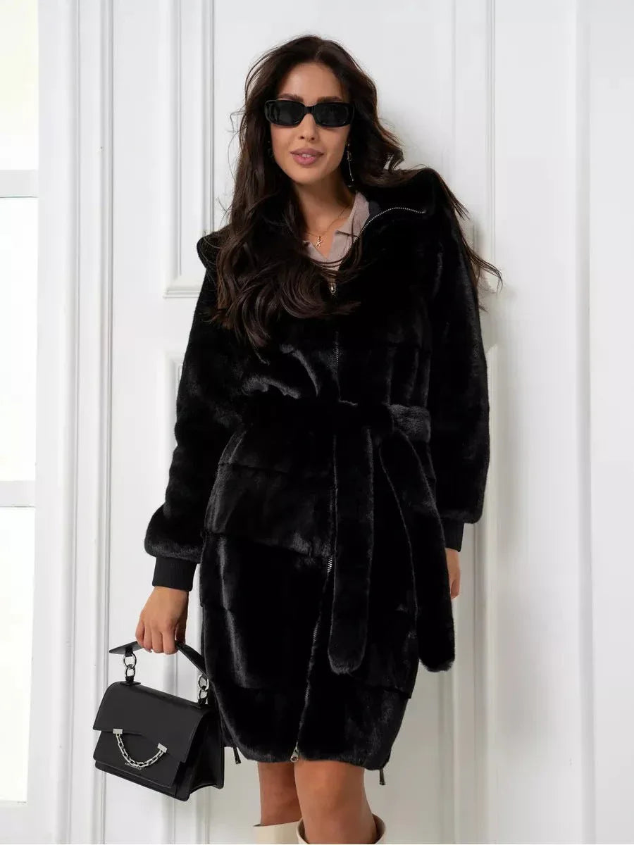 Woman wearing a black hooded faux fur coat with a belted waist and zipper closure.