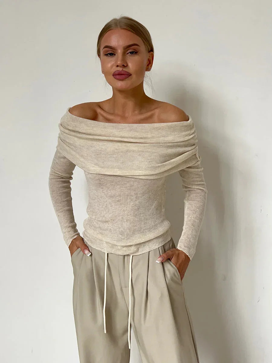 Front view of a woman in a beige off-the-shoulder ribbed knit sweater.