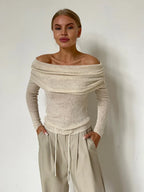 Front view of a woman in a beige off-the-shoulder ribbed knit sweater.